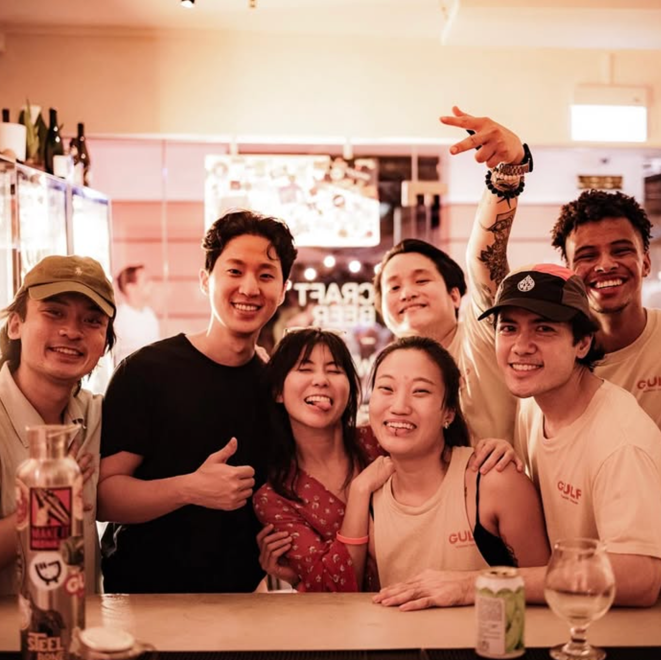 Group of friends posing together at a bar with drinks and a casual atmosphere.