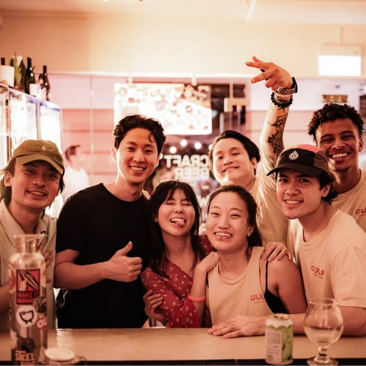 Group of friends posing together at a bar with drinks and a casual atmosphere.