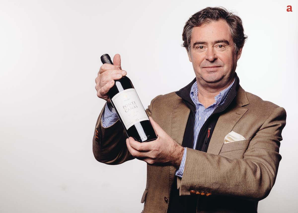 Man holding a wine bottle against a plain background